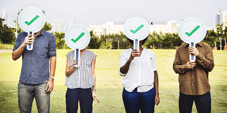 People holding voting signs over their faces